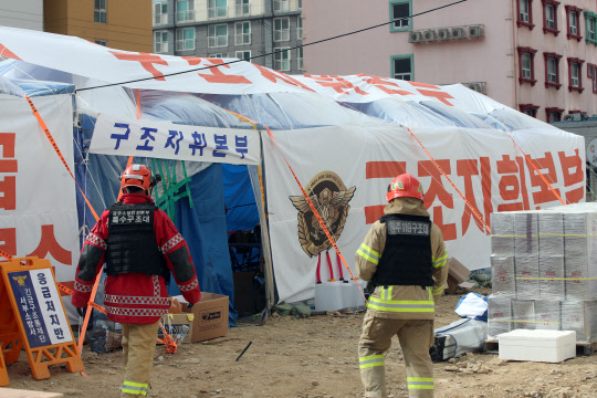 정부는 광주 화정동 신축 주상복합 아파트 붕괴사고와 관련하여 안경덕 고용노동부 장관을 본부장으로 하는 중앙사고수습본부를 23일부터 운영한다고 밝혔다. 22일 오전 광주 서구 화정아이파크 붕괴 현장 인근에 마련된 구조지휘본부에 소방대원들이 들어가고 있다. <연합뉴스>
